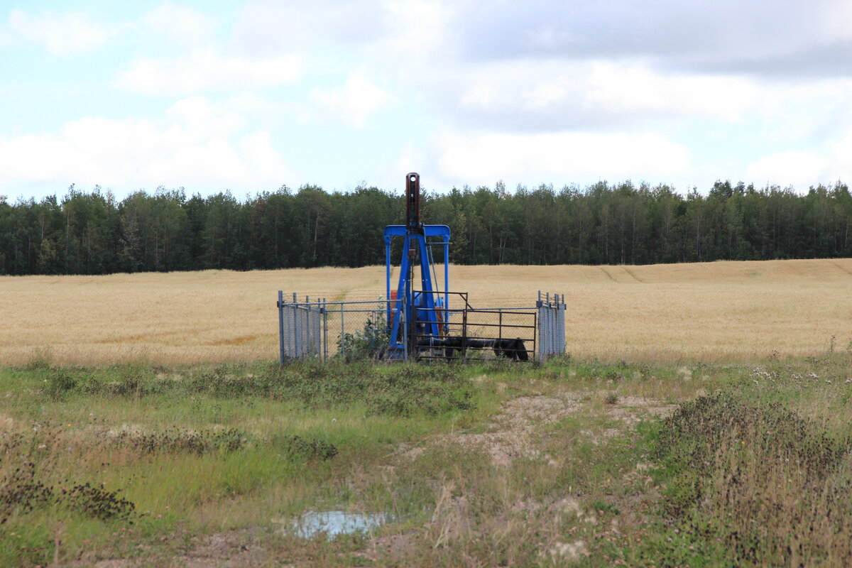 Aging oil pumpjack in rural Alberta field, representing the environmental and economic impact on rural communities